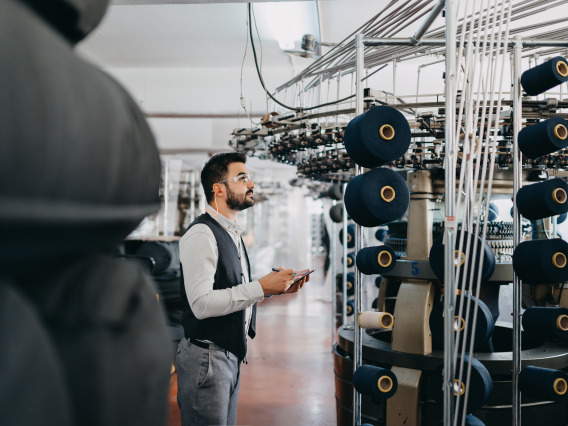 A man checking a machine in a cloth manufacturing factory